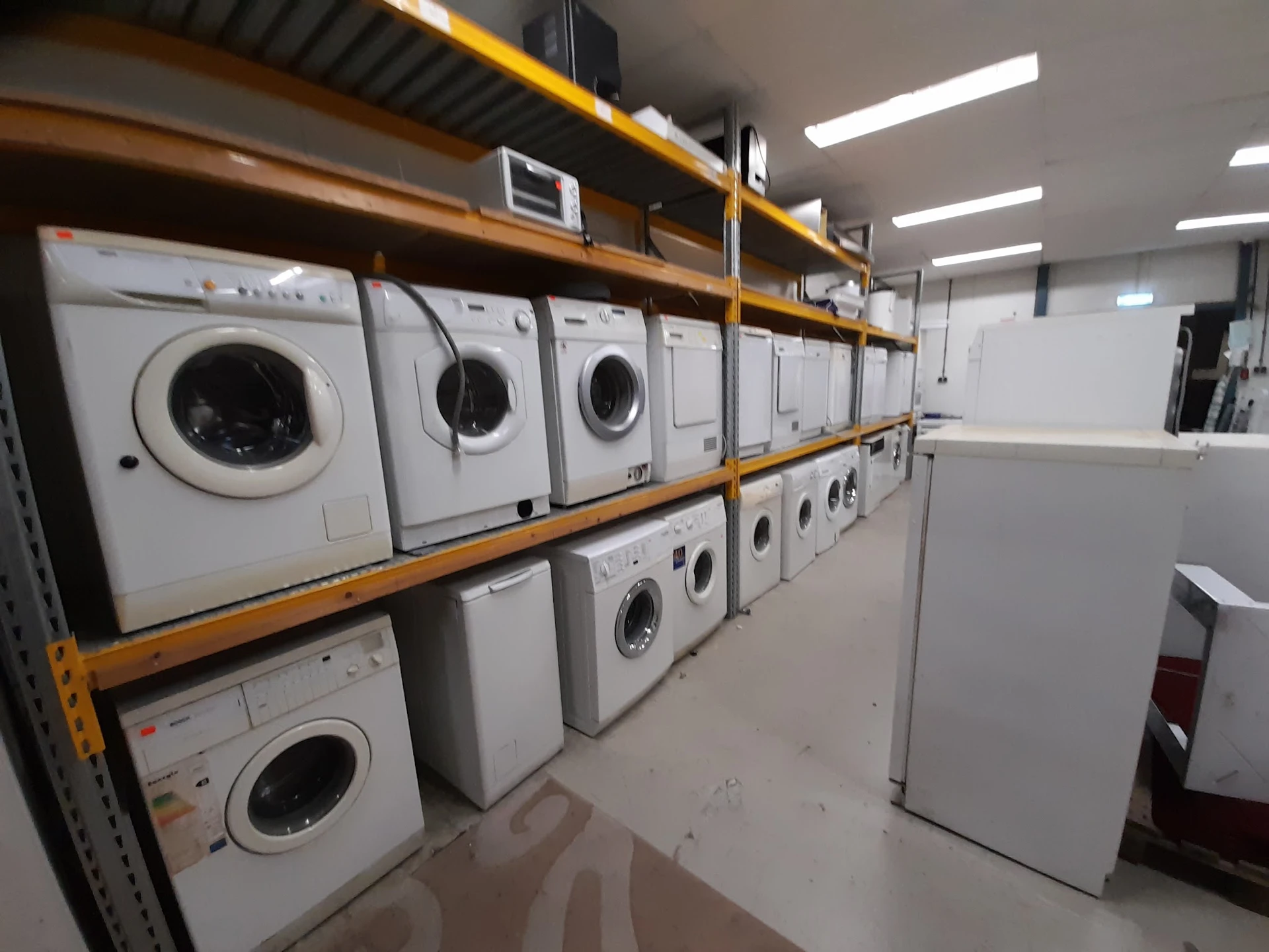 Stellingen met witgoedapparaten, voornamelijk wasmachines en drogers in verschillende maten