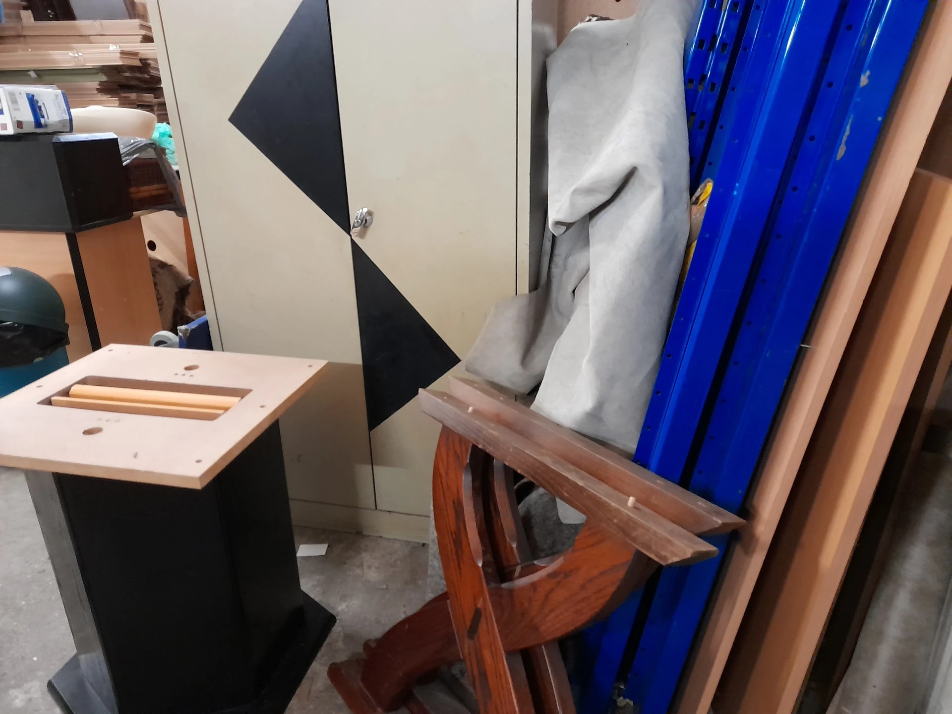 Tweedehands meubels en huishoudelijke artikelen: houten stoelen, blauwe plastic kratten en andere voorwerpen op een stoffige 