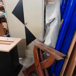 Tweedehands meubels en huishoudelijke artikelen: houten stoelen, blauwe plastic kratten en andere voorwerpen op een stoffige 