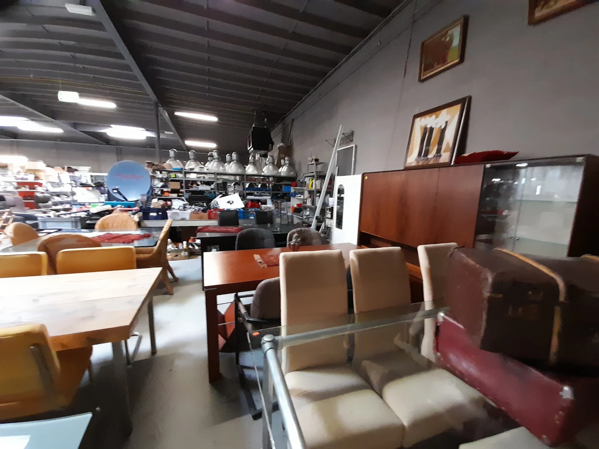 Winkelvloer met meubels: zetels, stoelen en tafels, stellingen met diverse artikelen op de achtergrond