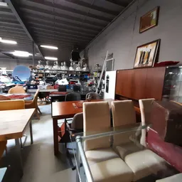 Winkelvloer met meubels: zetels, stoelen en tafels, stellingen met diverse artikelen op de achtergrond