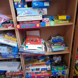 Houten stellingkast vol met dozen bordspellen, puzzels en speelgoed in een kringloopwinkel