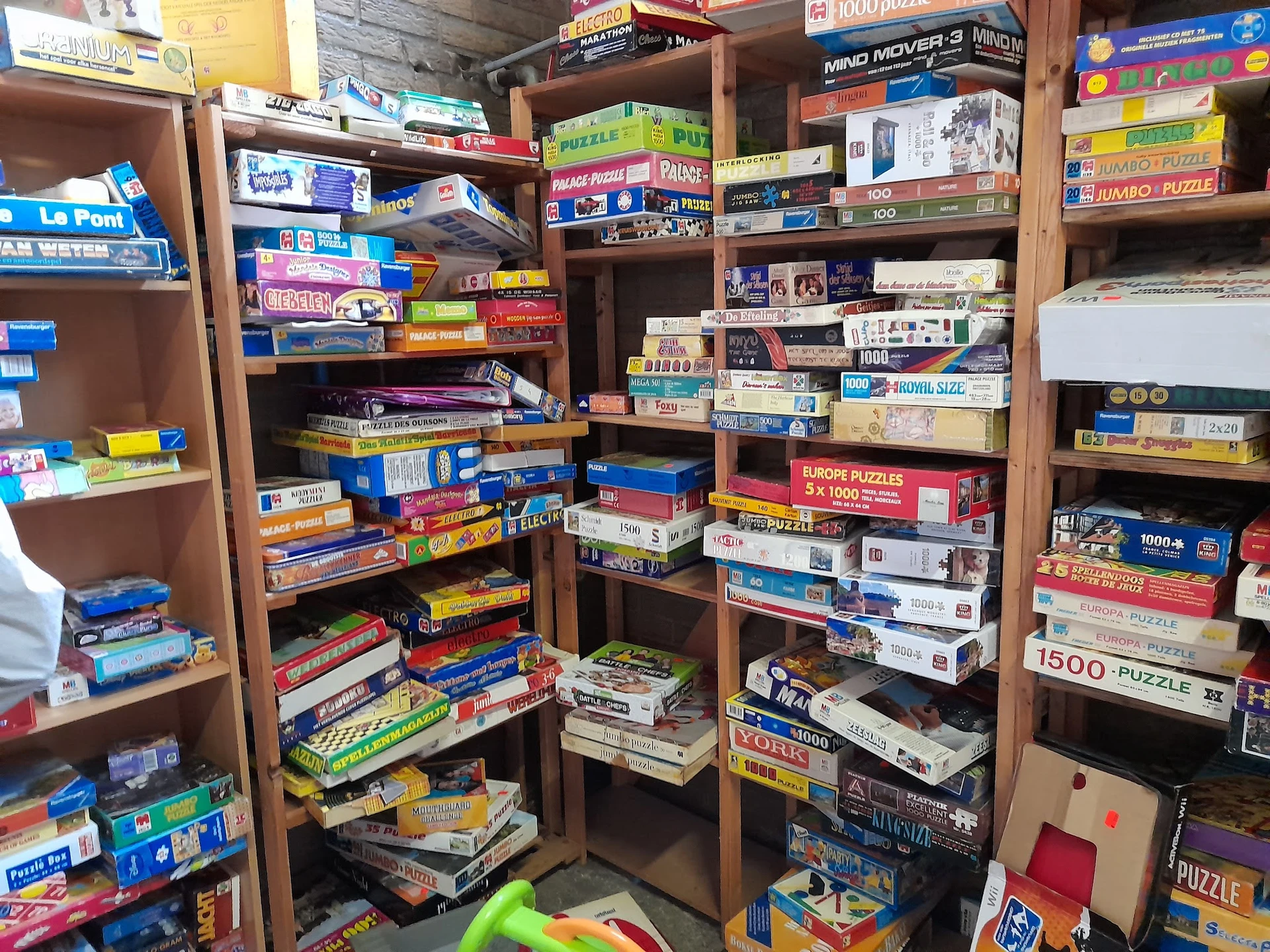 Houten stellingen volgestapeld met bordspellen, puzzels en andere speelgoed in verschillende kleuren