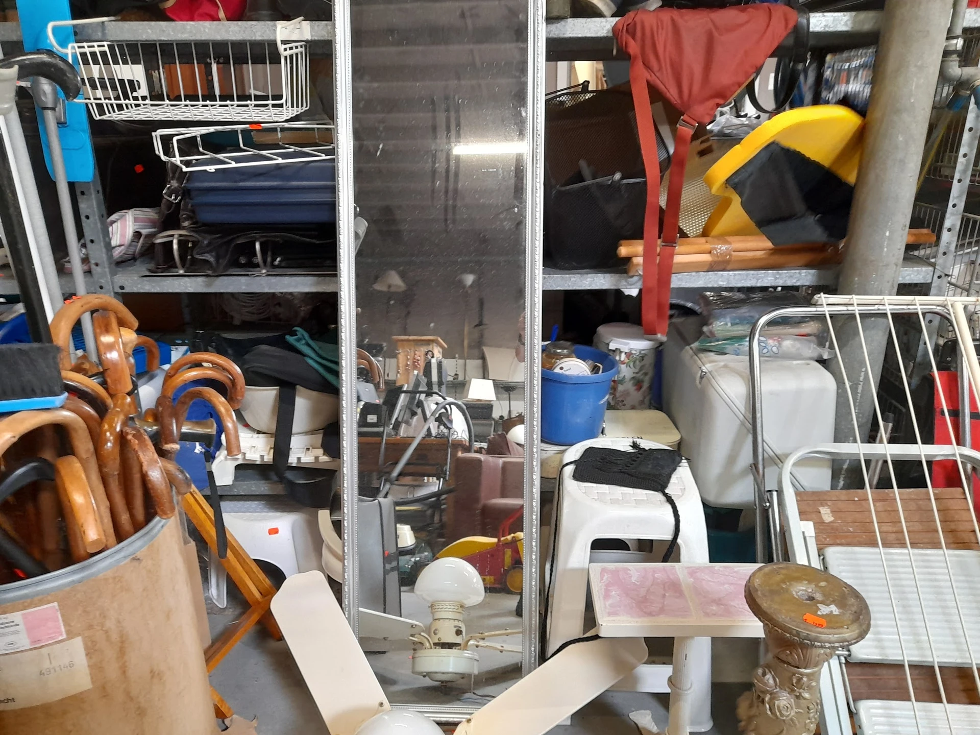 Overzicht van kringloopwinkel met stellingen vol diverse spullen, huishoudartikelen en kleding