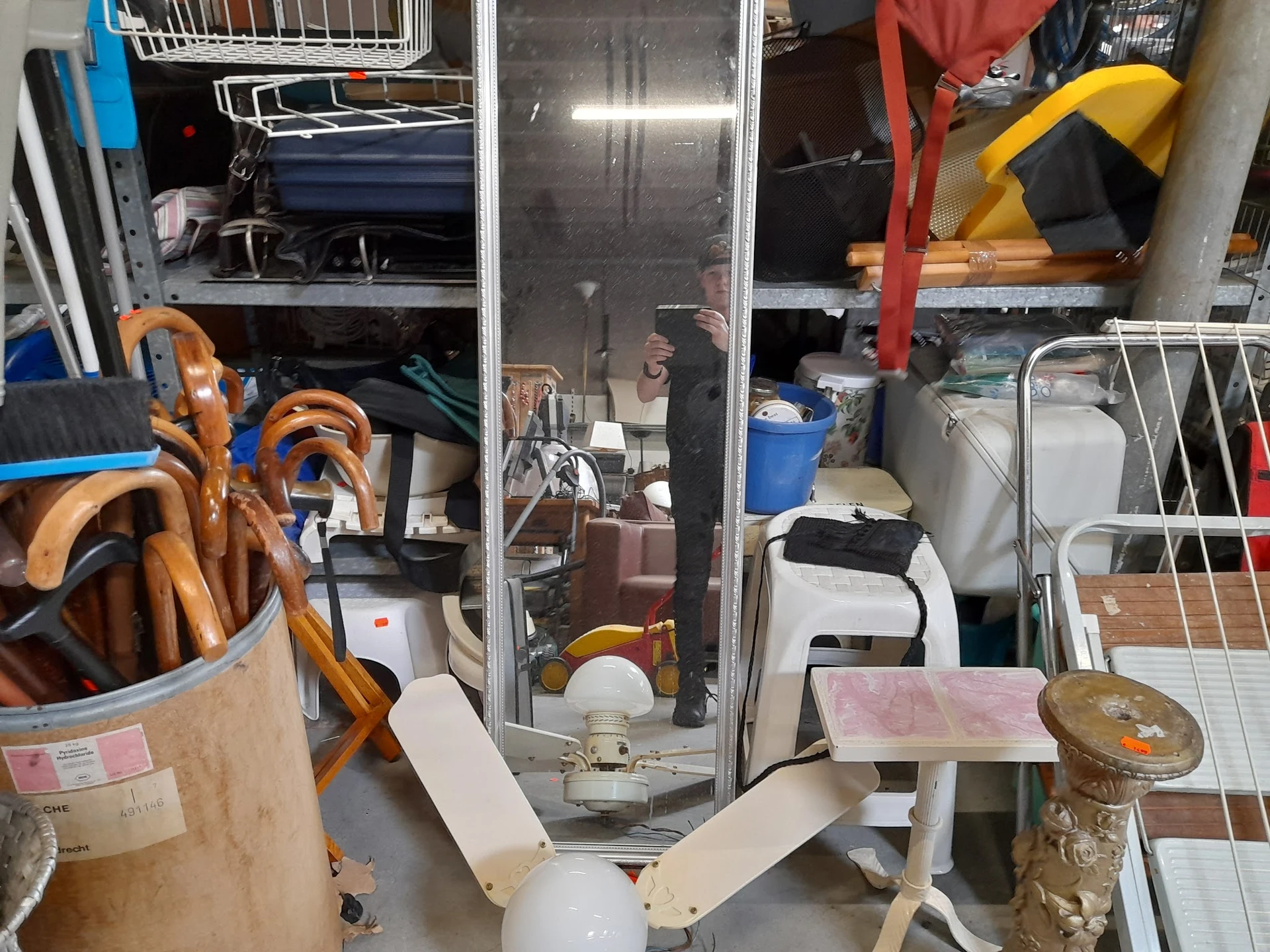 Volle stellingen en opgeslagen spullen in een kringloopwinkel, inclusief huishoudartikelen en meubels
