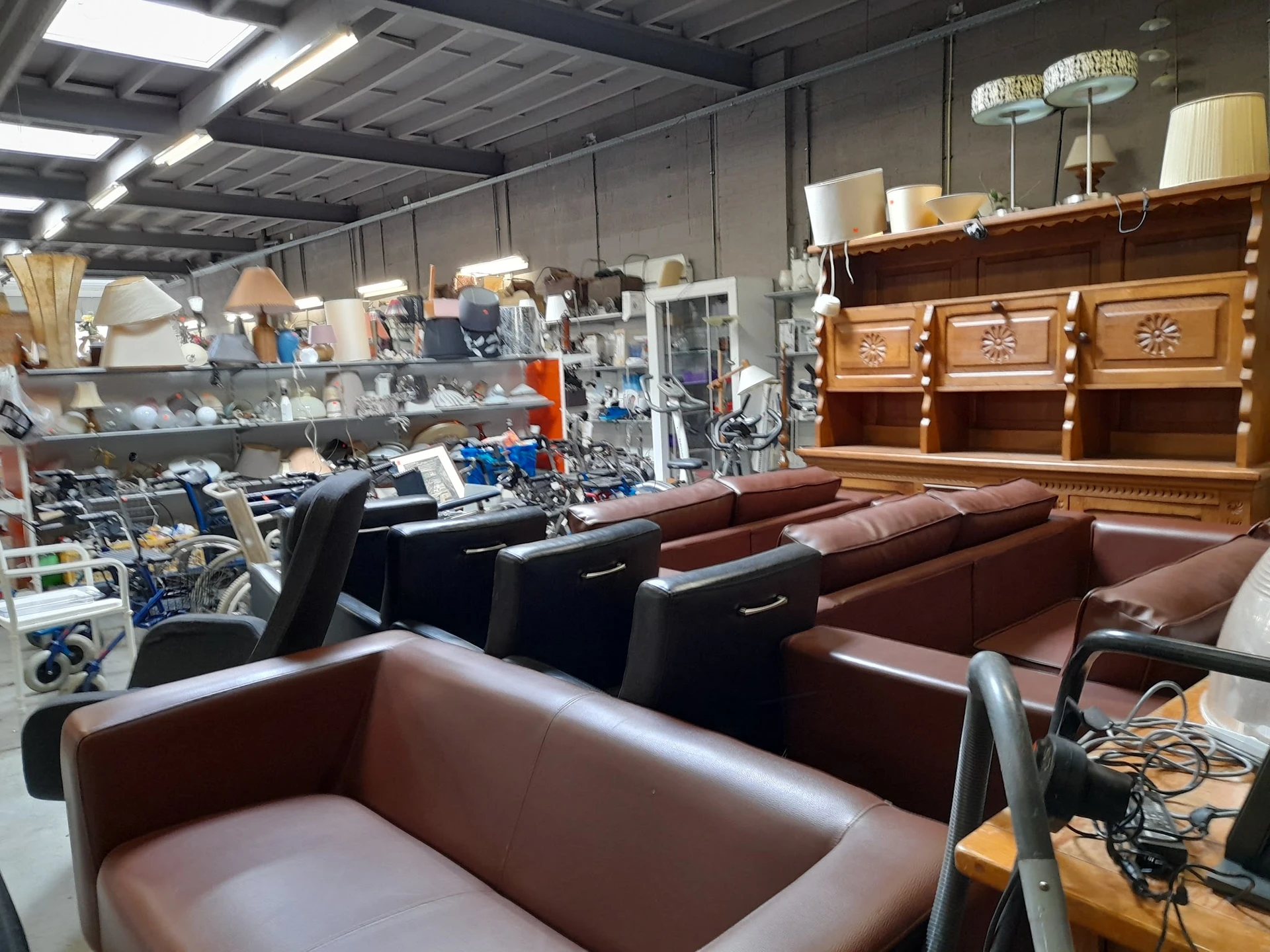 Winkelvloer met bruine fauteuils, banken en houten meubels in kringloopwinkel