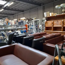 Winkelvloer met bruine fauteuils, banken en houten meubels in kringloopwinkel