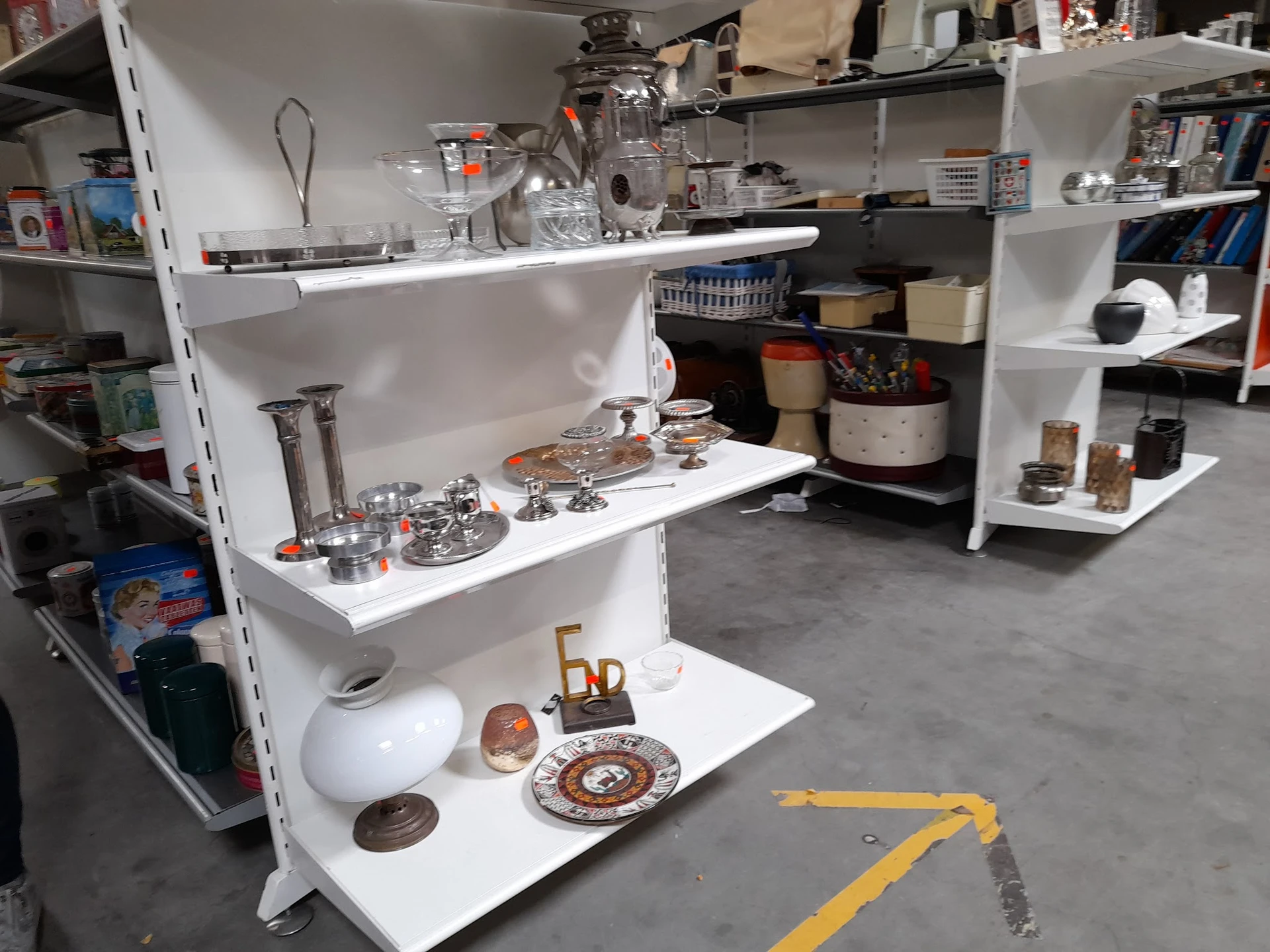 Witte stellingen met huishoudelijke artikelen zoals servies, glazen, decoratie en keukengerei