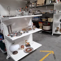 Witte stellingen met huishoudelijke artikelen zoals servies, glazen, decoratie en keukengerei
