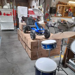 Blauwe kindergo-kart en trommel op kartonnen dozen in kringloopwinkel