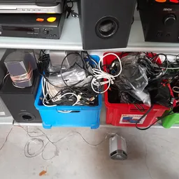 Blauwe en rode kunststofkisten met elektronische apparaten, kabels en accessoires op een werkblad