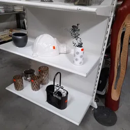 Witte stellingkasten met huishoudelijke artikelen: helm, plantenpot, kandelaar en handtas