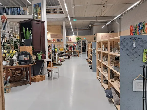 Ruim winkelbinnenruimte met houten stellingen, vintage meubels en decoratieve spullen