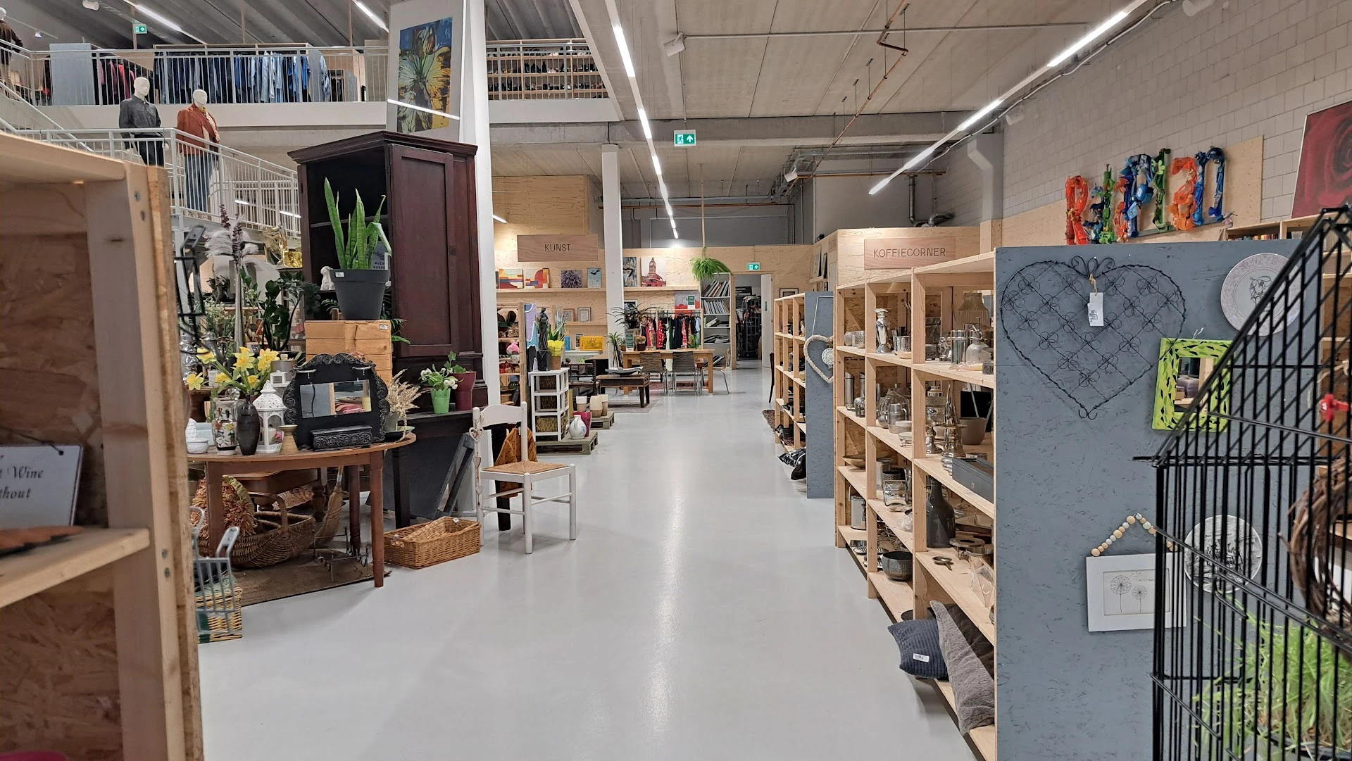 Ruim winkelbinnenruimte met houten stellingen, vintage meubels en decoratieve spullen