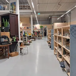 Winkelvloer van kringloopwinkel met houten stellingen, meubels en diverse spullen uitgestald