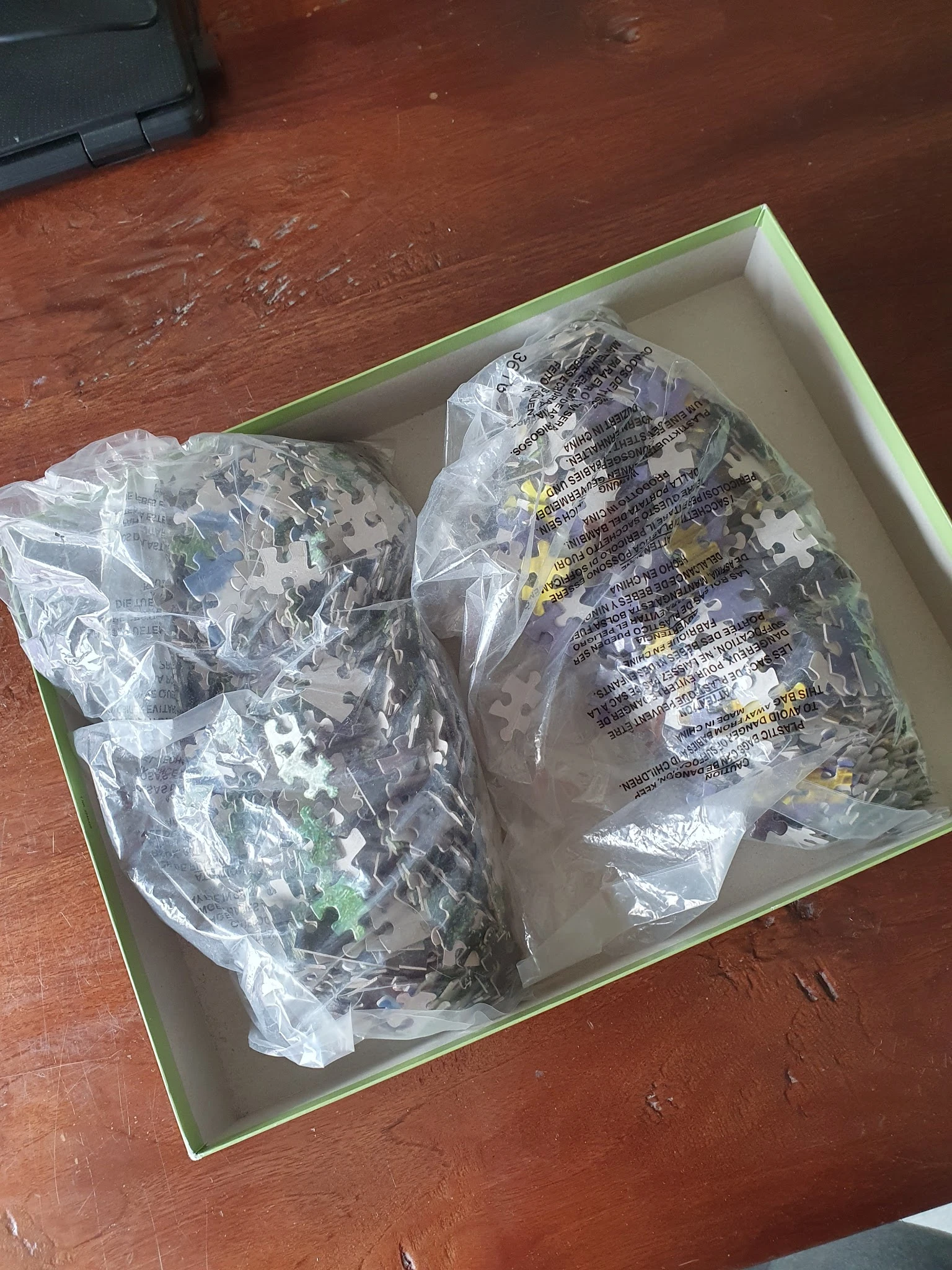 Twee verpakte puzzels in plastic folie in een wit doosje