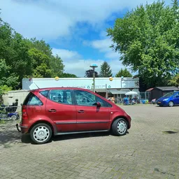 Rode auto op parkeerterrein voor kringloopwinkel