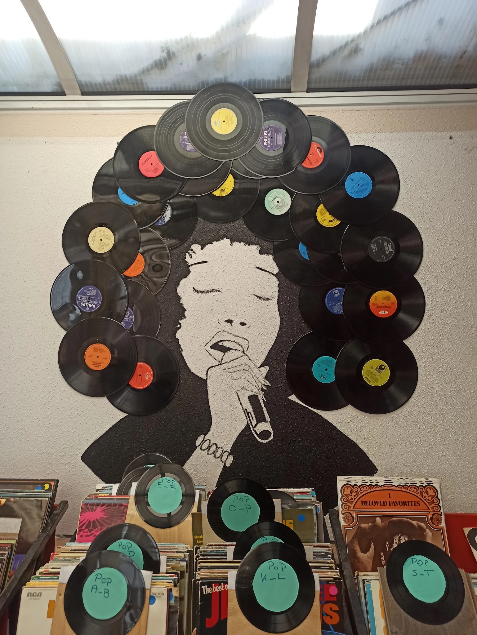 Kunstwerk gemaakt van vinyl platen met portret van een zingend gezicht in het centrum