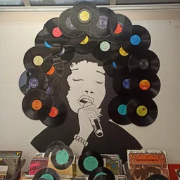 Kunstwerk gemaakt van vinyl platen met portret van een zingend gezicht in het centrum