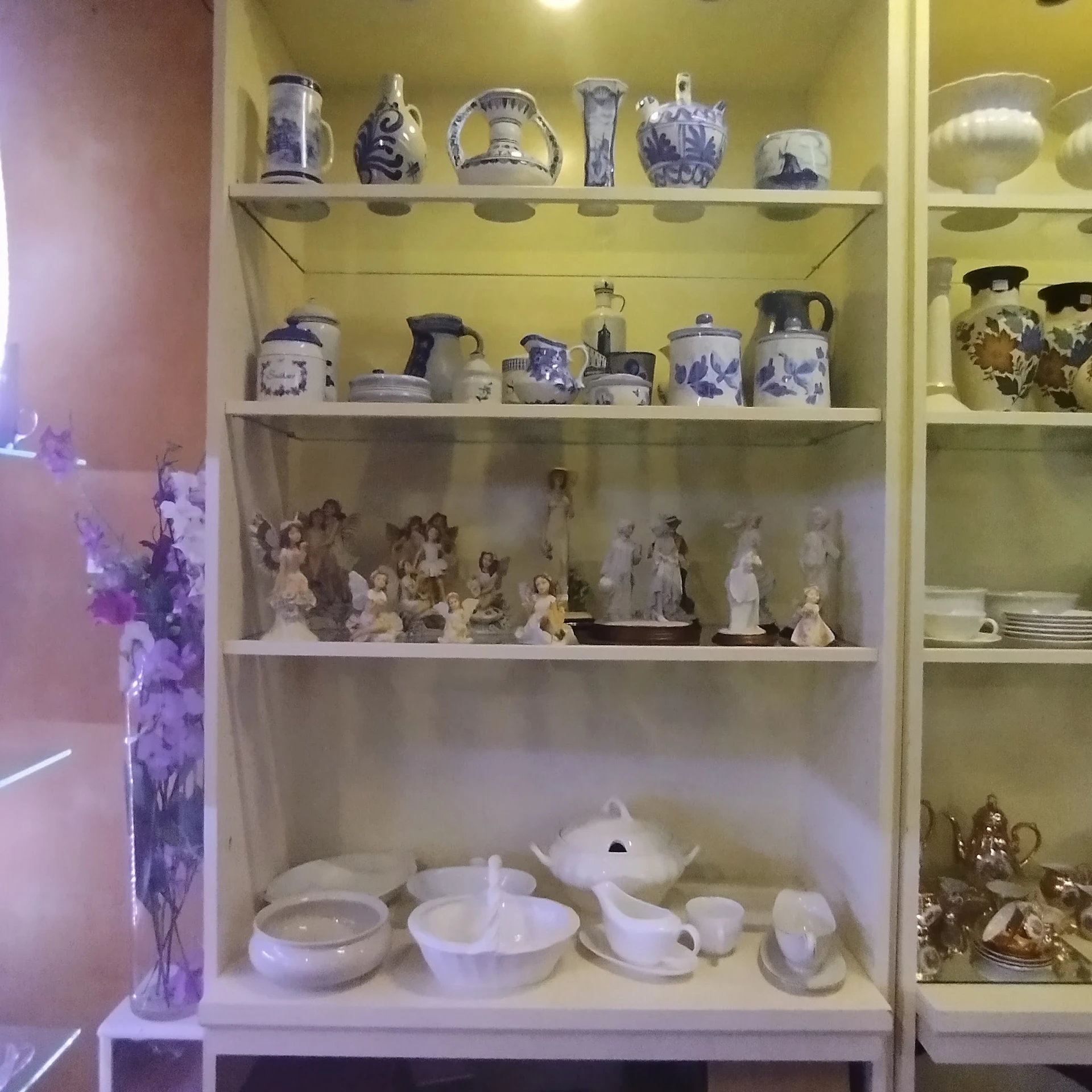 Glazen kast met verzameling aardewerk, servies en beeldjes in blauw-wit en goud
