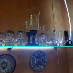 Glazen vazen en drinkglazen op verlichte schappen in de winkel