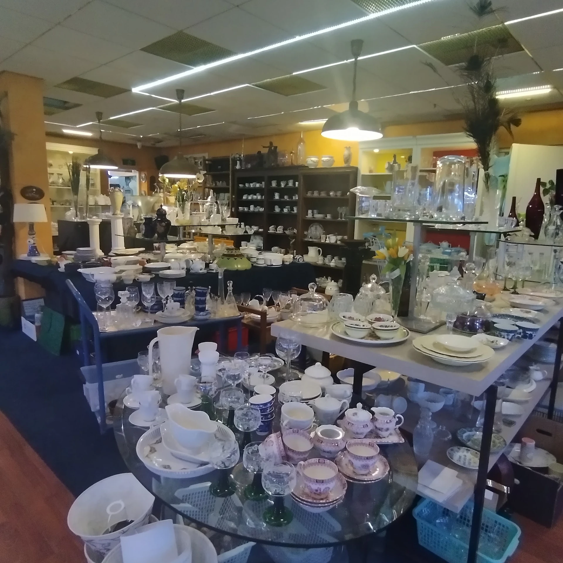 Uitgestalde serviesgoed, glazen en huishoudartikelen in de kringloopwinkel