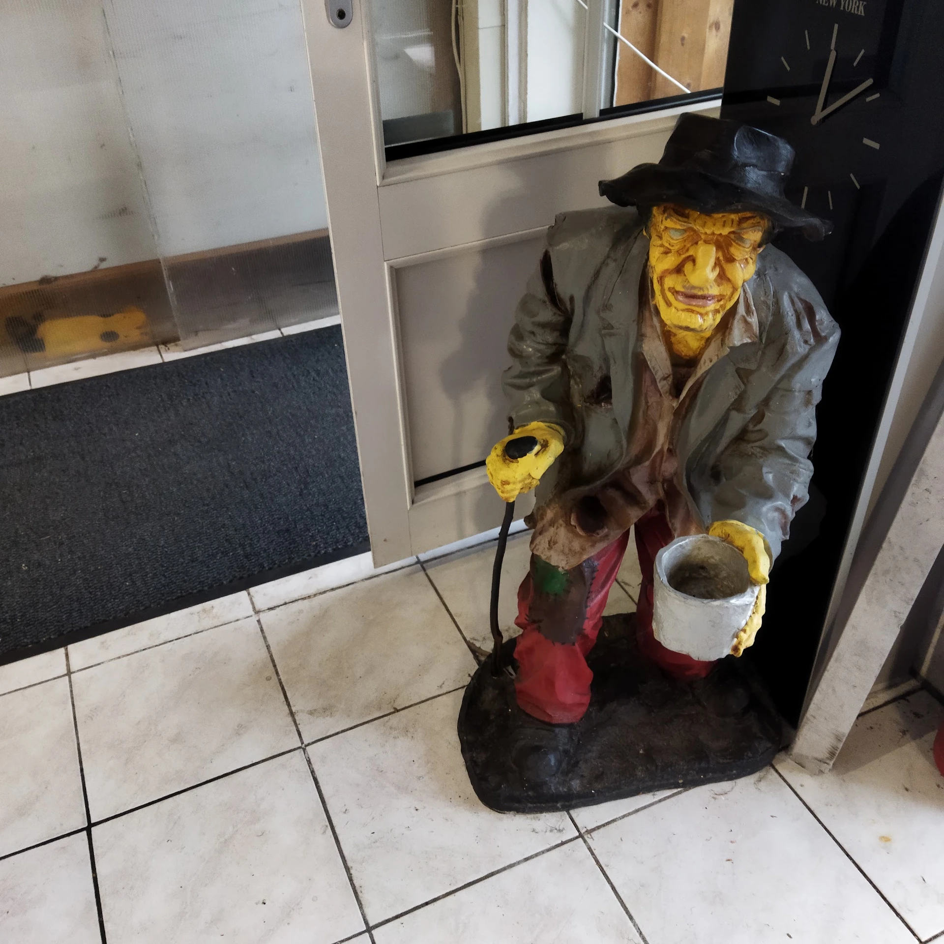 Decoratief Halloween-figuur van een heks met geel gezicht, bruine jas en rode rok in een kringloopwinkel