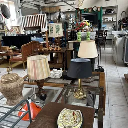 Verschillende meubels en huishoudelijke artikelen uitgestald in de winkel, waaronder lampen, stoelen, tafels en decoratieve i
