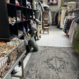 Winkelvloer van kringloopwinkel met rekken met kleding, dozen met spullen en diverse uitgestalde goederen