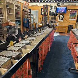 Winkelinterieur met lange rij vinylplatenrekken en zwarte luidsprekerboxen langs rode decoratieve panelen