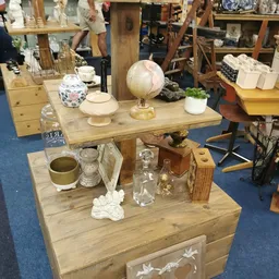Houten display tafel met diverse huishoudelijke artikelen: glazen potten, decoratieve bollen, plantenpot en andere secondhand