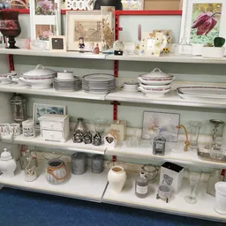 Stellingen met servies, glazen, decoratieve voorwerpen en huishoudartikelen netjes uitgestald