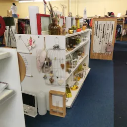 Witte stellingkast met diverse huishoudelijke spullen, decoratieitems en gele accessoires uitgestald