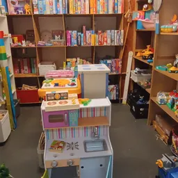 Speelgoedafdeling in kringloopwinkel met speelkeuken, boeken en speelgoed op stellingen