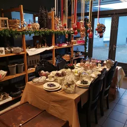 Gedekte tafel met borden, glazen en eten in een ruimte met grote ramen en kerstversiering
