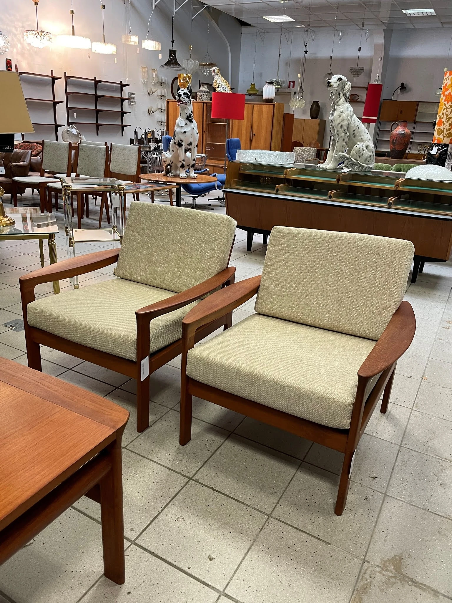 Twee vintage fauteuils met houten frame en beige stoffen bekleding naast elkaar in de winkel