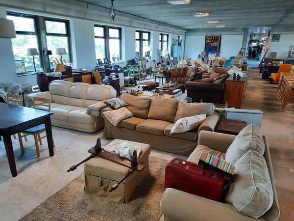 Ruim winkelinterieur met uitgestalde meubels zoals banken, stoelen en kasten op houten vloer