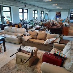 Ruim winkelinterieur met uitgestalde meubels zoals banken, stoelen en kasten op houten vloer
