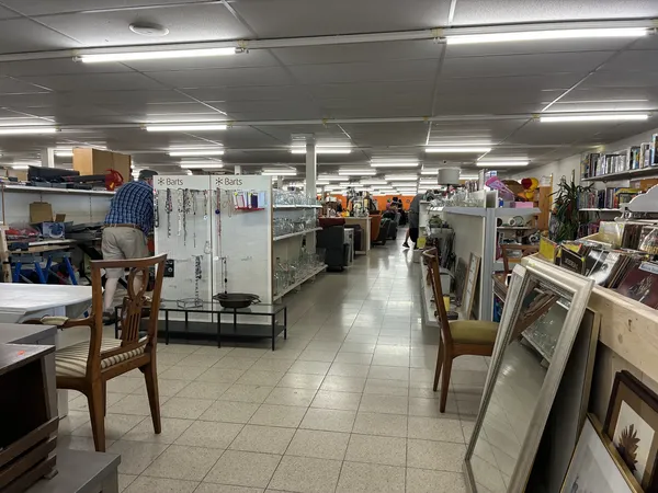 Winkelinterieur met stellingen, tafels en stoelen, display-frames aan de rechterkant en winkelmedewerkers in het achtergrondg