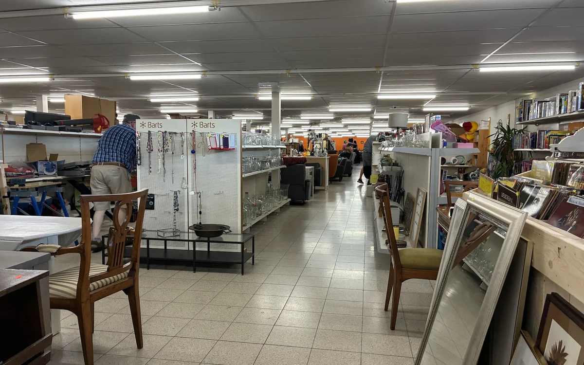 Winkelinterieur met stellingen, tafels en stoelen, display-frames aan de rechterkant en winkelmedewerkers in het achtergrondg