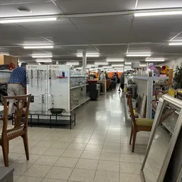 Winkelinterieur met stellingen, tafels en stoelen, display-frames aan de rechterkant en winkelmedewerkers in het achtergrondg