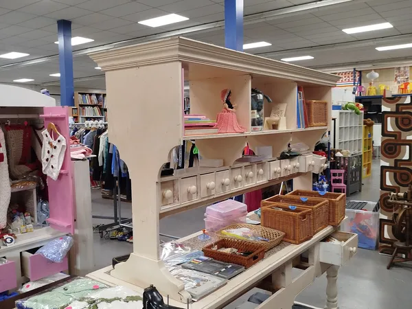 Winkelvloer met stellingen, kleding aan rekken, opbergkuipen en decoratieve items in een kringloopwinkel