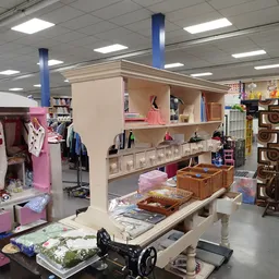 Winkelvloer met stellingen, kleding aan rekken, opbergkuipen en decoratieve items in een kringloopwinkel
