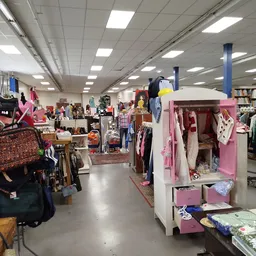 Ruime winkelruimte met kledingrekken, kasten en diverse tweedehands spullen uitgestald