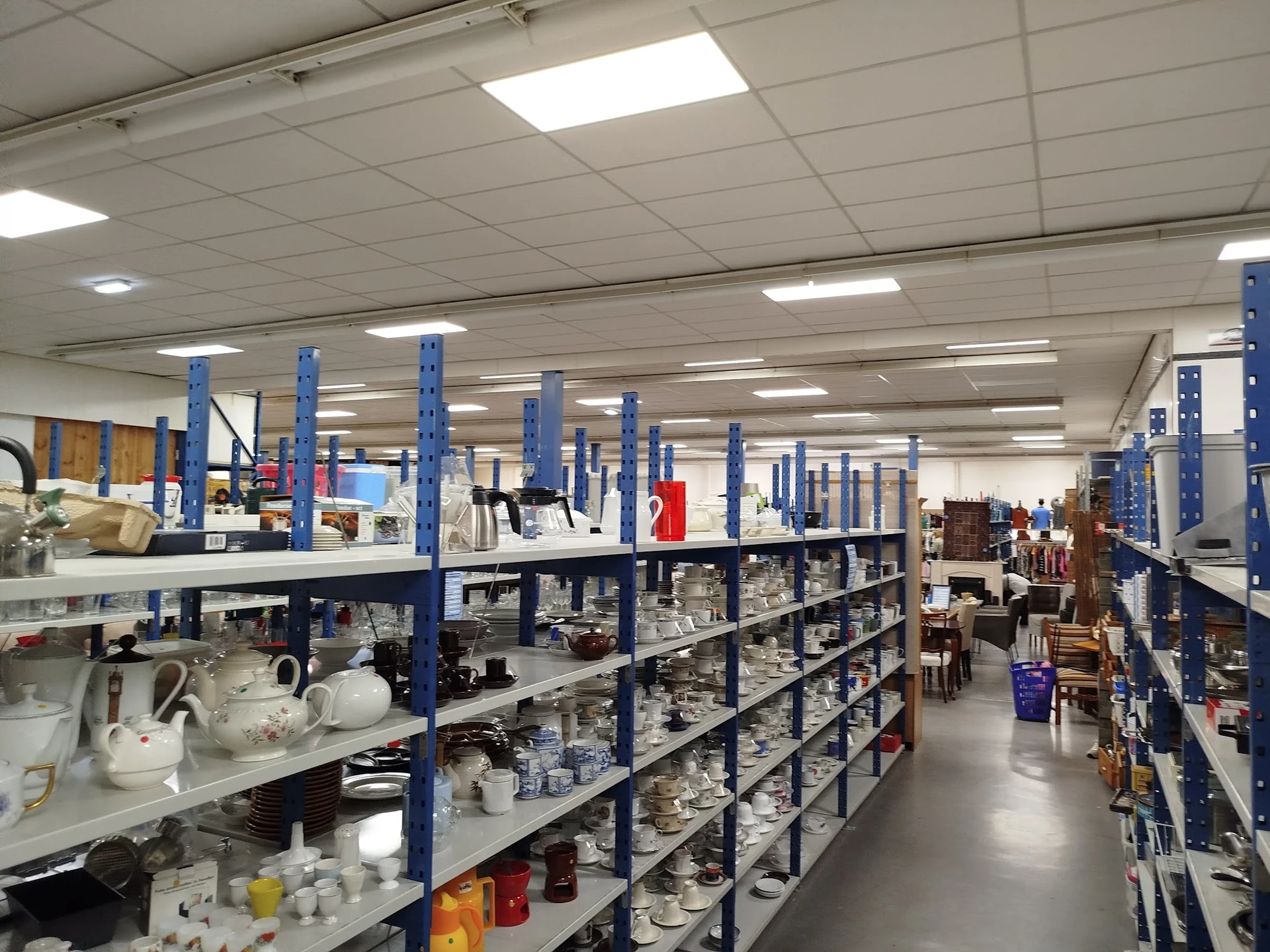 Winkelinterieur met blauwe stellingen vol huishoudartikelen en serviesgoed