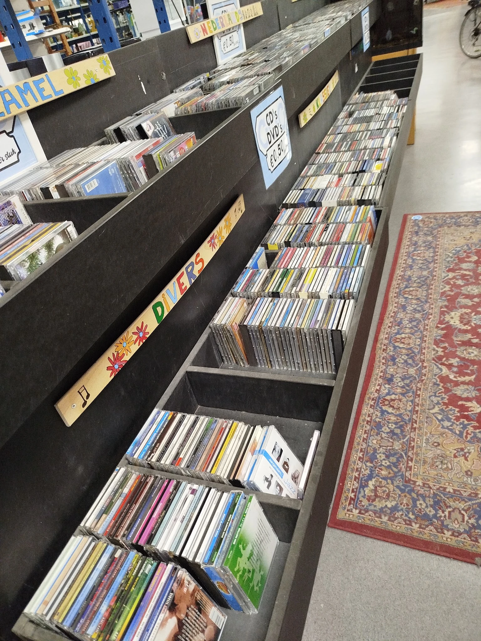 Rekken met CD's en DVD's uitgestald in een kringloopwinkel