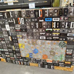 Grote collectie cassettebandjes en cd's uitgestald op een zwart panneel in de winkel