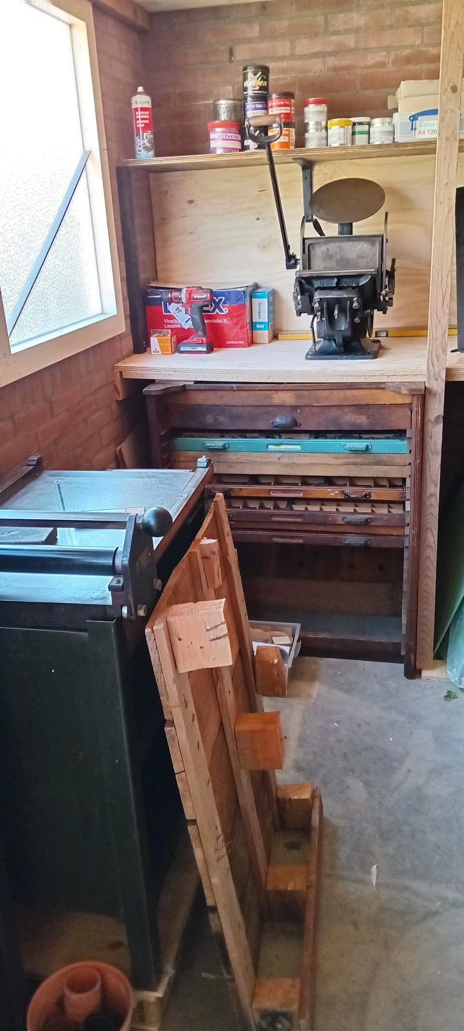 Houten meubel met uitschuifbare laden in verschillende kleuren, gedeeltelijk geopend in een kringloopwinkel