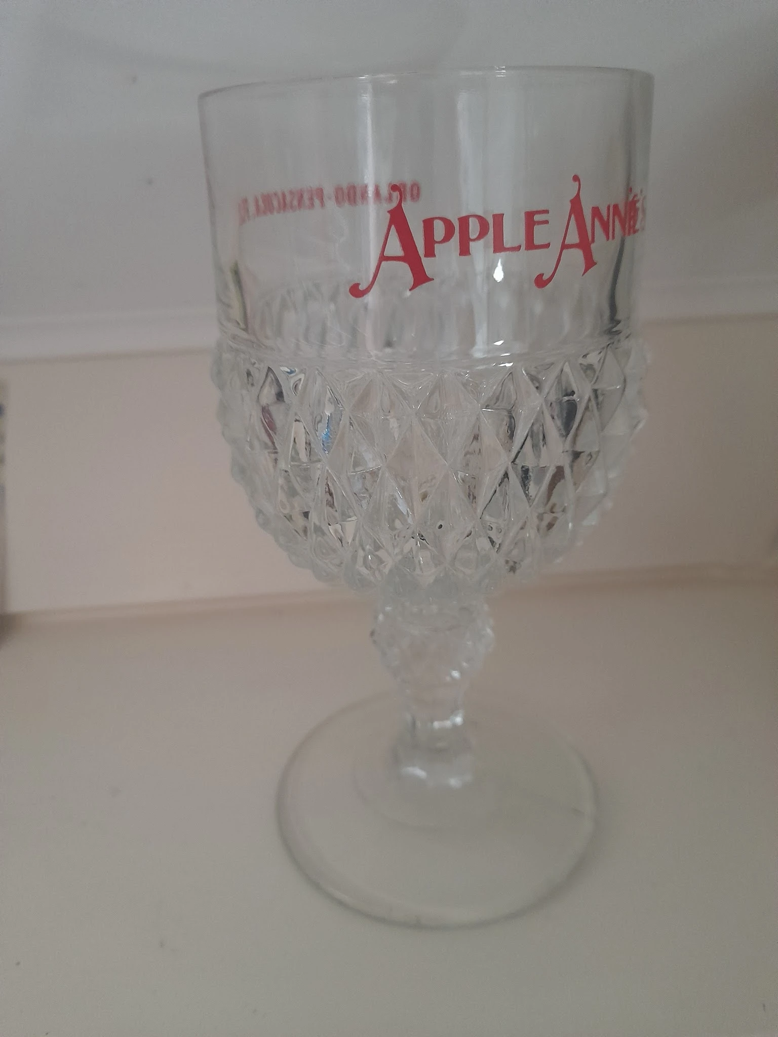 Kristallen wijnglas met rood Apple-logo aan de bovenkant