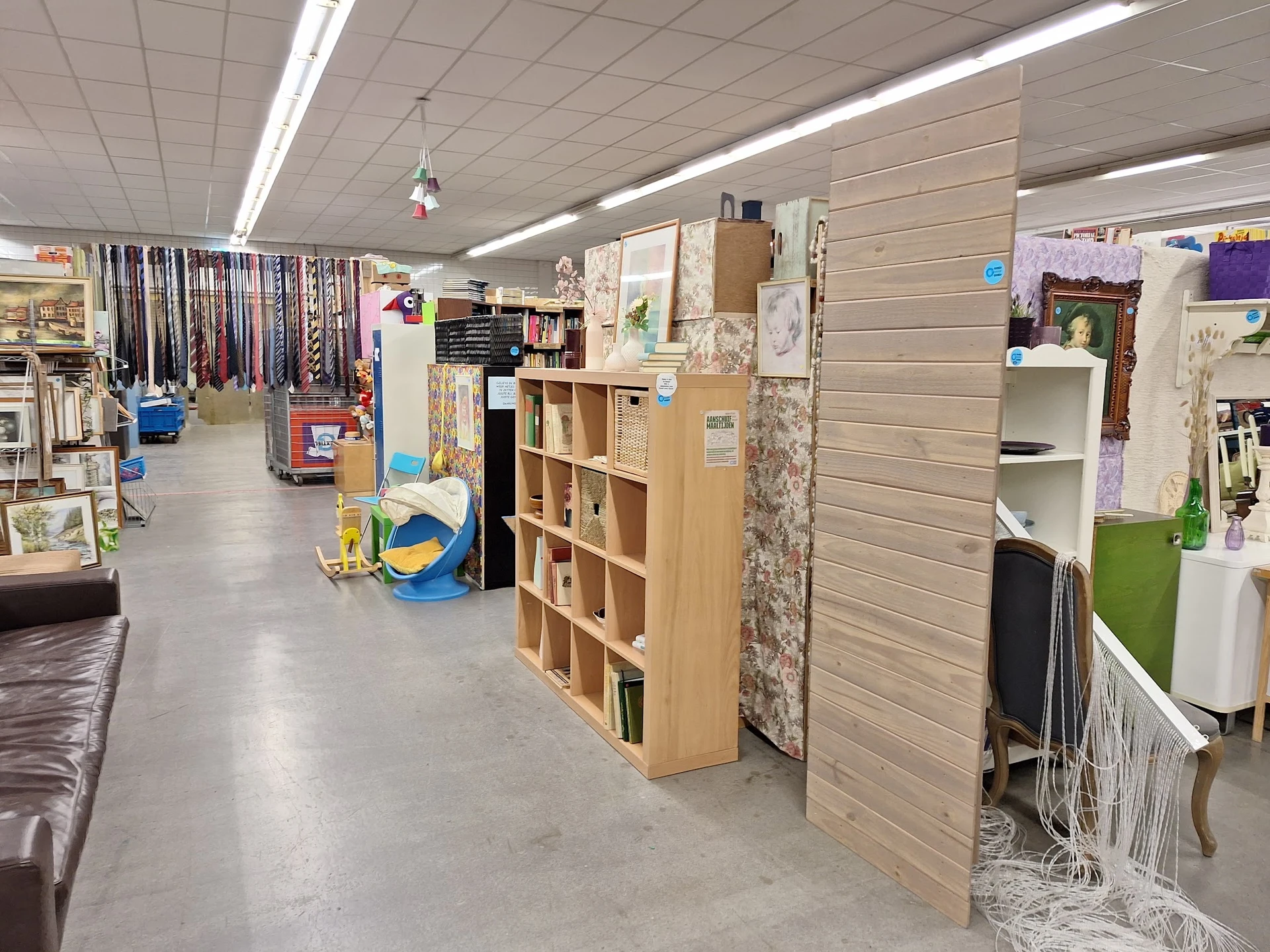 Winkelinterieur met houten stellingen, uitgestalde spullen en diverse merchandise langs de wanden
